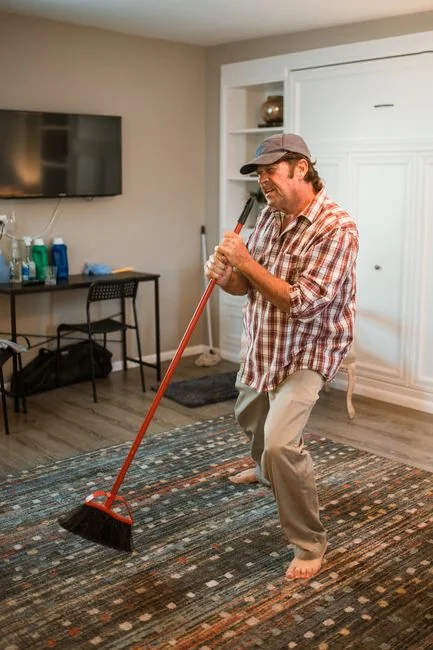 Side view of a young ethnic male in uniform cleaning the floor with a mop while working in a retro-style restaurant
